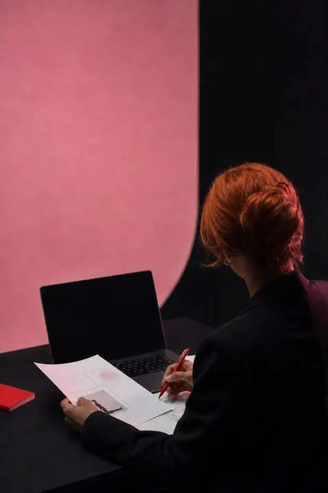 Faceless ginger-haired consultant working at a desk